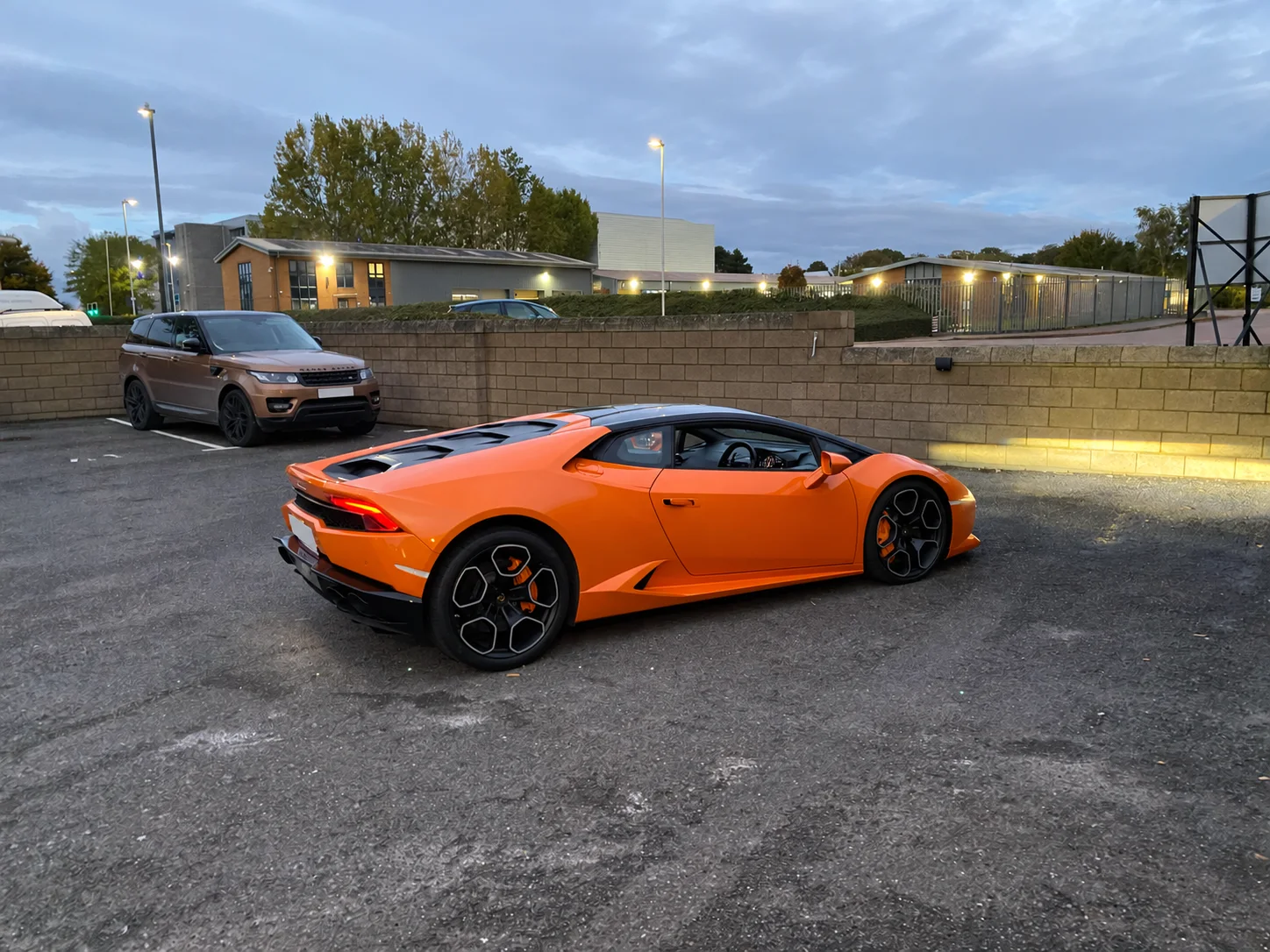 Orange Lamborghini on a forecourt at dusk