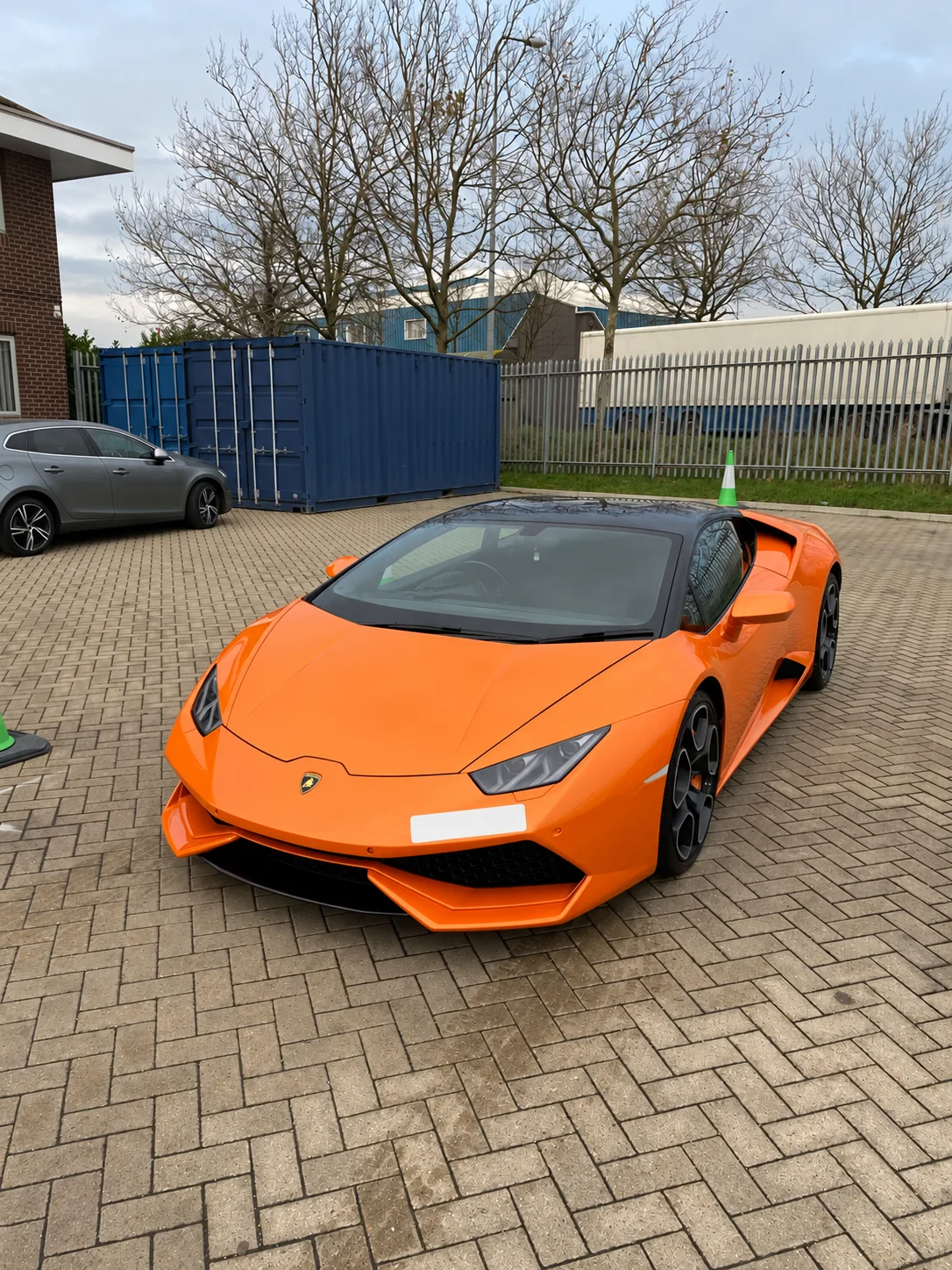 Front view of an orange Lamborghini on a paved forecourt
